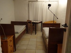 Das zweite Zimmer "Wiese" mit zwei Betten, die auch als Doppelbett gestellt werden können, einem Sessel, Einem Schrank, Stühlen und einem Tisch. Hinterm Vorhang befindet sich ganz flächig ein Fenster. Von hier kannst Du die Rehe und den Mäusebussard beobachten